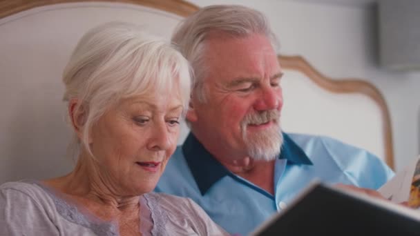 Close Van Glimlachend Gepensioneerd Senior Paar Bed Thuis Kijken Door — Stockvideo