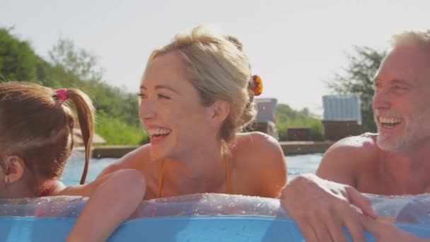 多代人微笑的家庭在暑假里的形象 轻松自在地漂浮在充气的空气床上 在游泳池里飞溅 慢镜头 — 图库视频影像