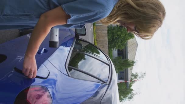 Pionowe Wideo Kobiety Zewnątrz Podłączającej Kabel Ładujący Samochodu Elektrycznego Kręcone — Wideo stockowe