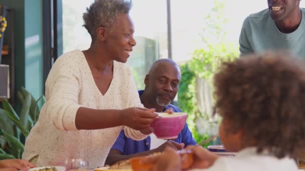 Multi Generation Οικογένεια Κάθεται Γύρω Από Τραπέζι Στο Σπίτι Τρώγοντας — Αρχείο Βίντεο