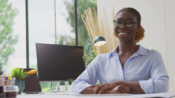 一个面带微笑的女商人 戴着眼镜坐在总公司的写字台前慢吞吞地笑着的画像 — 图库视频影像