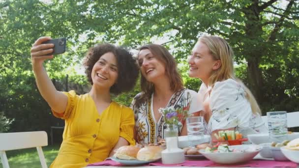 妇女们在手机上摆出自拍的姿势 坐在花园外面一起吃饭 动作缓慢 — 图库视频影像