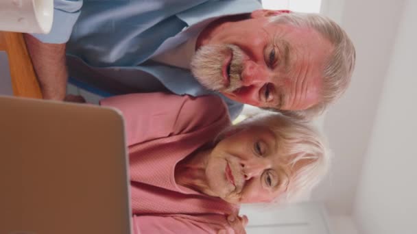 家族や友人へのビデオ通話を作る自宅でラップトップと引退したシニアカップルの垂直ビデオ スローモーションで撮影 — ストック動画