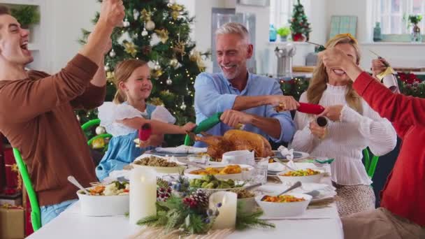 Mehrgenerationenfamilie Feiert Weihnachten Hause Und Zieht Cracker Vor Dem Gemeinsamen — Stockvideo