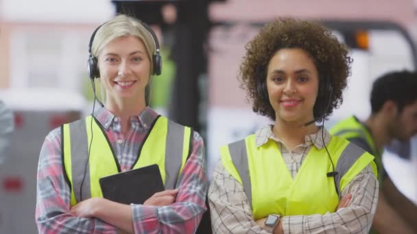 二人の女性労働者の肖像は 両方一緒にデジタルタブレット折り畳み腕を使用して流通倉庫でヘッドセットを身に着けている スローモーションで撮影 — ストック動画