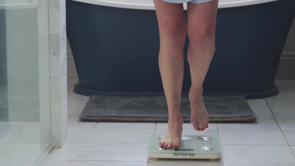 与体重增加有关的绝经期成熟女性 在浴室的天平上站立 慢动作射击 — 图库视频影像
