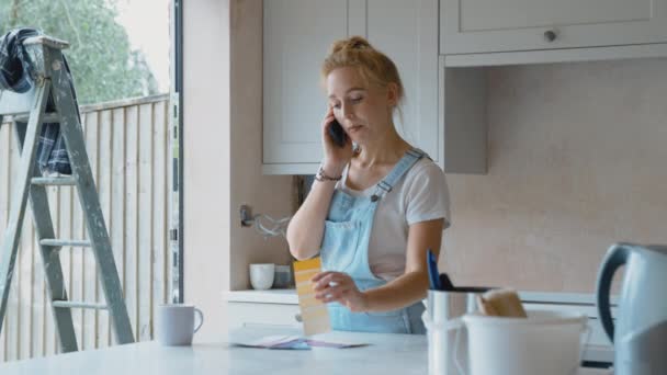 女人在家里装修厨房 看着彩绘的石板 一边用手机聊天 动作缓慢 — 图库视频影像
