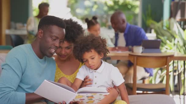 Multi Generation Familie Med Forældre Sidder Sofaen Derhjemme Læse Bog – Stock-video