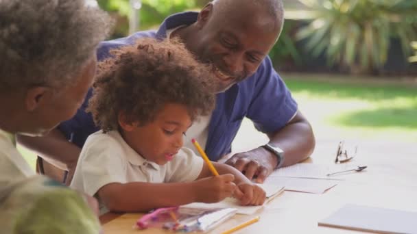 Multi Generation Family Grandparents Helping Grandson Homework Home Sitting Table — Stock Video