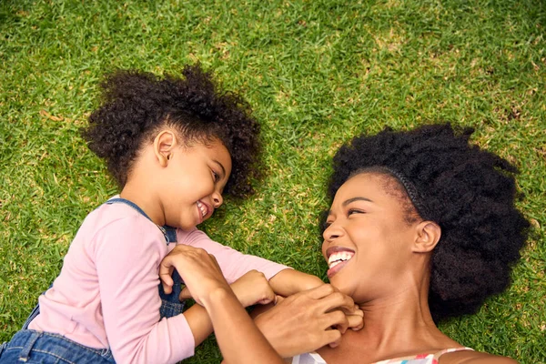 笑顔の母と娘が一緒に庭で草の上に横たわっている — ストック写真