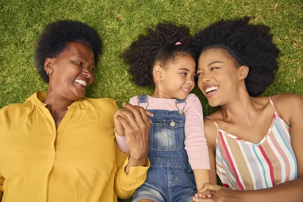 一緒に庭で草の上に横たわっている多世代の女性の家族の笑顔のオーバーヘッドショット — ストック写真