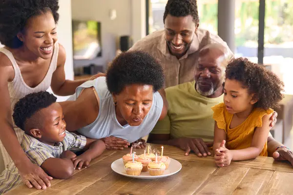 マルチジェネレーションファミリーは 家でケーキとろうそくの周りのテーブルで祖母の誕生日を祝います — ストック写真