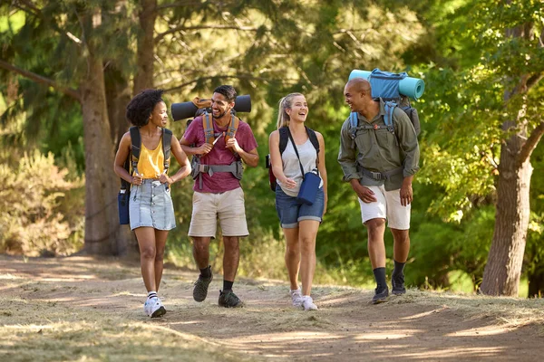 Group Of Friends With Backpacks On Vacation Hiking Through Forest Countryside Together