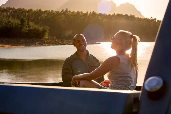 Couple In Pick Up Truck On Road Trip By Lake At Sunset
