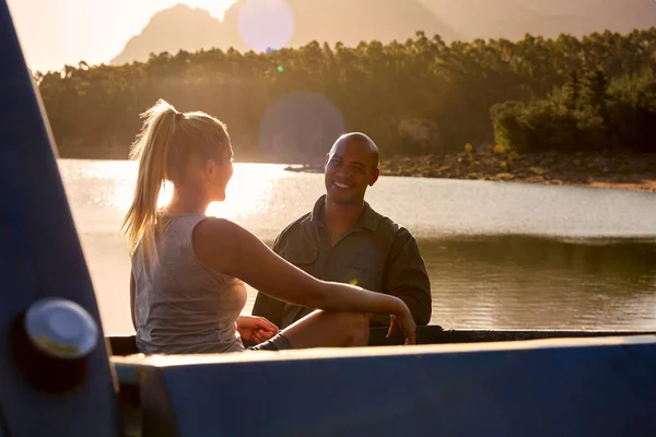 Couple In Pick Up Truck On Road Trip By Lake At Sunset