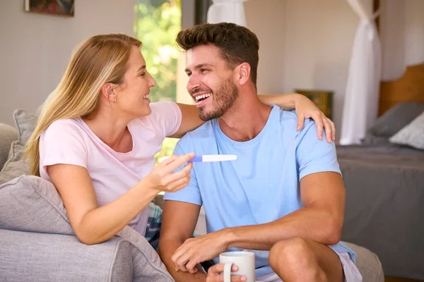 Excited Couple In Bedroom At Home Celebrating Positive Pregnancy Test Result