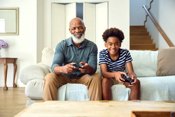 爷爷和孙子在家里玩电子游戏与男孩一起庆祝胜利 — 图库照片