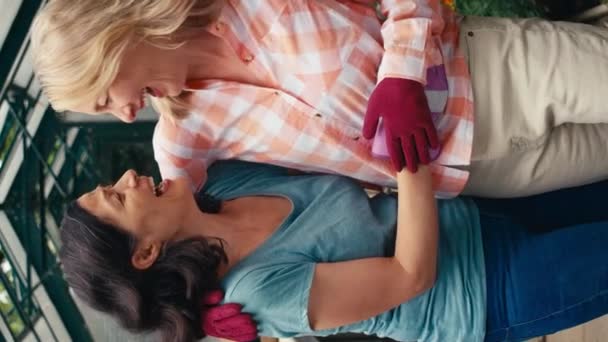 同じ性別を愛するの垂直ビデオ肖像画 成熟した女性カップルは一緒に自宅のガーデニングで温室で働くように抱擁 スローモーションで撮影 — ストック動画