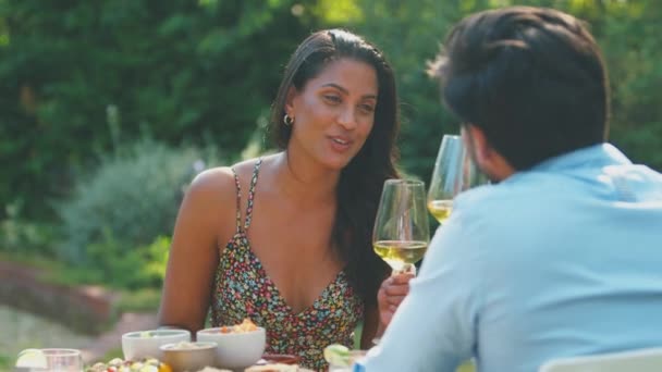 自宅で庭で屋外の食事を楽しむカップルは 白ワインのグラスで乾杯をする スローモーションで撮影 — ストック動画