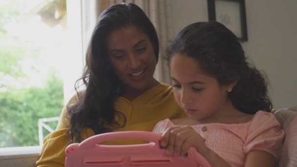 妈妈和女儿坐在沙发上 坐在家里客厅里玩掌上明珠的电脑游戏 — 图库视频影像