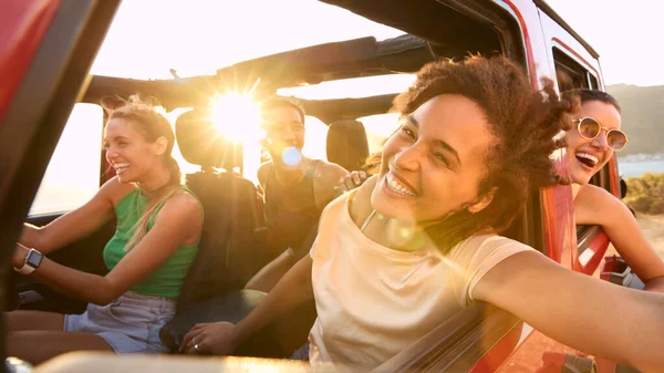 Portrait Of Laughing Female Friends Having Fun In Open Top Car On Road Trip