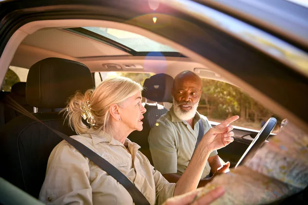 Confused Senior Couple On Day Trip Out Driving In Car Reading Map Looking Lost