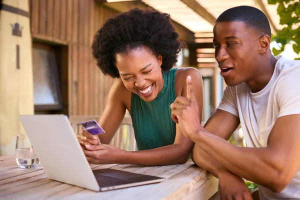 Excited Couple With Credit Card Using Laptop At Home To Book Holiday Or Shop Online