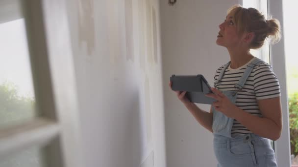 拥有数字平板翻新房间的妇女在家里获得在线灵感拿着数字平板电脑看着测试人员在墙上画彩带 动作缓慢 — 图库视频影像