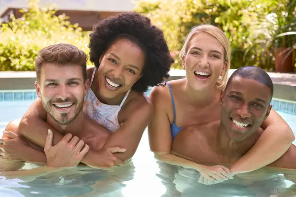 Portrait Of Group Of Smiling Multi-Cultural Friends On Holiday In Swimming Pool