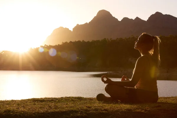 Woman Meditating Doing Yoga By Lake And Mountains At Sunset