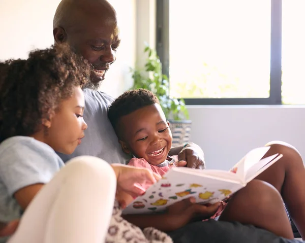 Nonno Seduto Sul Divano Casa Leggere Libro Con Nipoti — Foto Stock