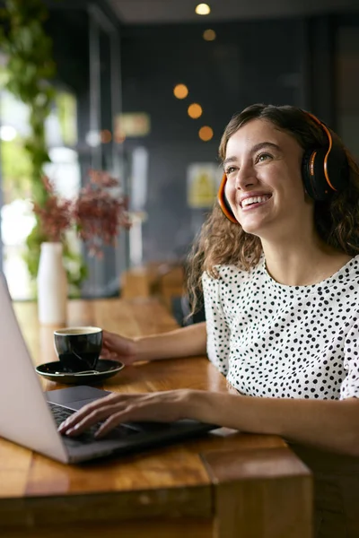 Businesswoman Wearing Wireless Headphones Working On Laptop In Cafe Or Office