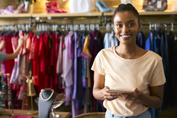Portrait Of Female Owner Or Worker In Fashion Clothing Store Checking Stock With Digital Tablet