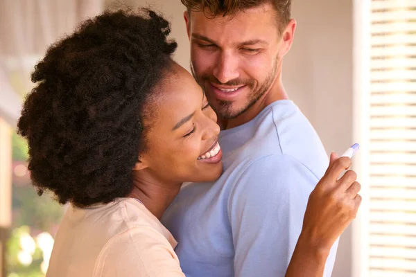 Knuffelen Multi Raciale Paar Slaapkamer Thuis Vieren Positieve Zwangerschap Test — Stockfoto