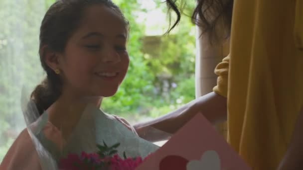 自宅で誕生日や母の日を祝うために花と自家製のカードの母親の束を与える娘の近く — ストック動画