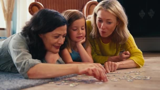 同性家庭 有两个成熟的妈妈和女儿躺在地板上一起做拼图游戏 动作缓慢 — 图库视频影像