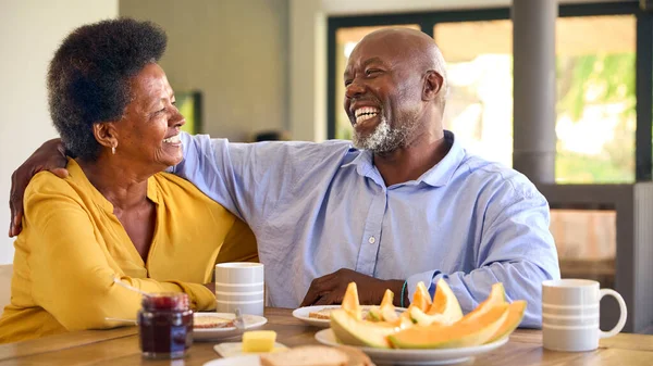 Senior Couple At Home Enjoying Breakfast Around Table Together