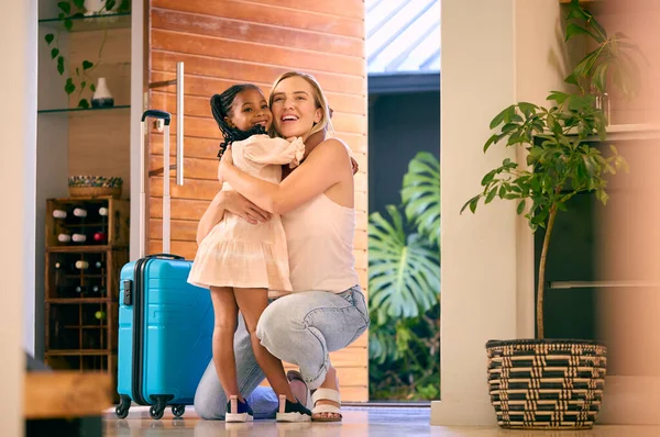 Daughter Greeting Mother Returning Home With Luggage From Trip Away