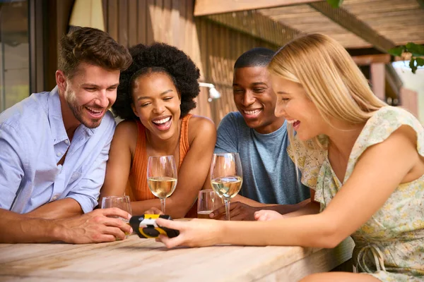 Group Of Smiling Multi-Cultural Friends Looking At Retro Camera Outdoors At Home Drinking Wine Together