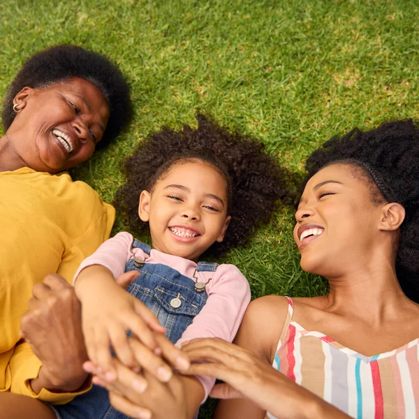 Overhead Shot Of Smiling Multi-Generation Female Family Lying On Grass In Garden Together