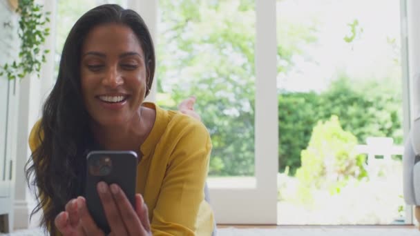 Kobieta Domu Leżąca Podłodze Salonie Streamując Film Telefonu Komórkowego Śmiejąc — Wideo stockowe