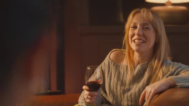 ソファーでリラックスし 居心地の良い火の前でワインを飲む2人の女性の友人 — ストック動画