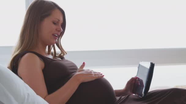 Sidevisning Gravid Kvinne Som Ligger Sengen Hjemme Ser Film Digital – stockvideo