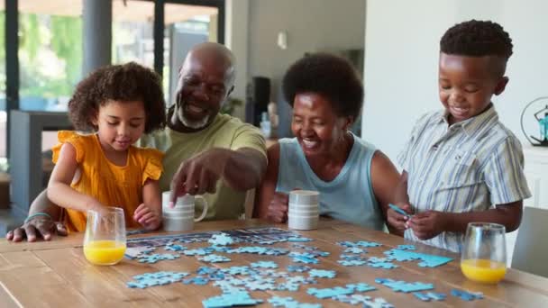Familia Con Abuelos Nietos Divirtiéndose Haciendo Rompecabezas Juntos Sentados Alrededor — Vídeo de stock
