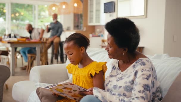 Grandmother Granddaughter Sitting Reading Book Sofa Home Multi Generation Family — Stock Video