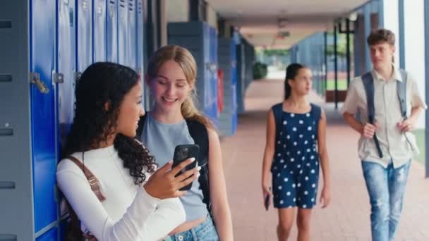 ロッカーで携帯電話でソーシャルメディアやインターネットを見ている2人の女子高校生 スローモーションで撮影 — ストック動画