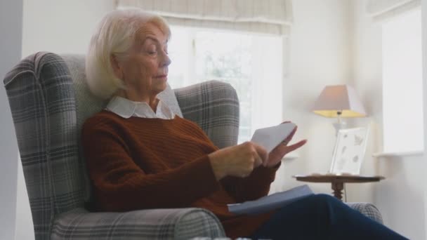 忧心忡忡的老年妇女在家里拿着便携式散热器 看着生活能源危机期间的能源账单 慢镜头拍摄 — 图库视频影像