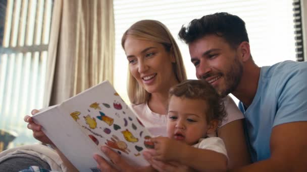 Familia Sentada Sofá Casa Con Los Padres Leyendo Libro Con — Vídeos de Stock