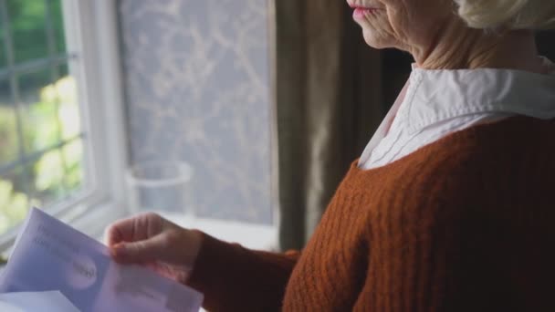 Ηλικιωμένη Γυναίκα Στέκεται Δίπλα Στο Παράθυρο Στο Σπίτι Ανοίγοντας Λογαριασμό — Αρχείο Βίντεο