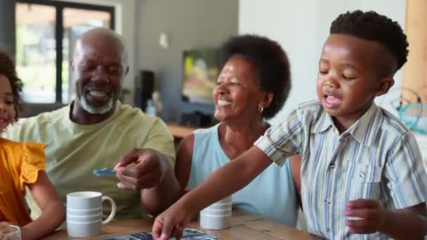 祖父母和孙子孙女一起玩拼图游戏的家庭在家里围坐在桌子旁 动作缓慢 — 图库视频影像